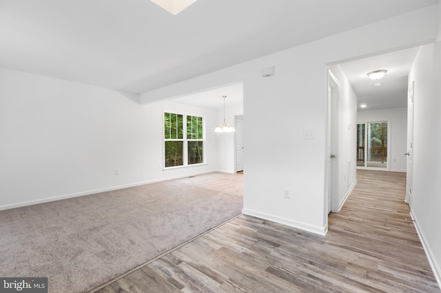 spare room featuring an inviting chandelier and light hardwood / wood-style flooring