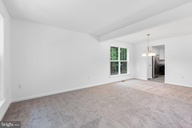 carpeted empty room with beamed ceiling and a notable chandelier