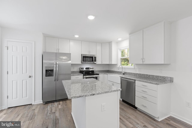 kitchen featuring white cabinets, light hardwood / wood-style flooring, a kitchen island, and appliances with stainless steel finishes