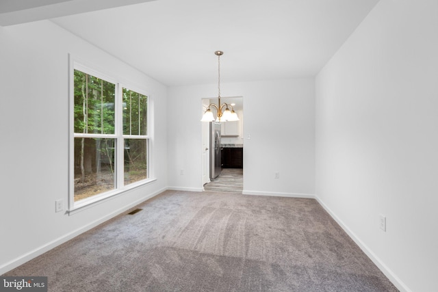 unfurnished dining area with carpet flooring and an inviting chandelier