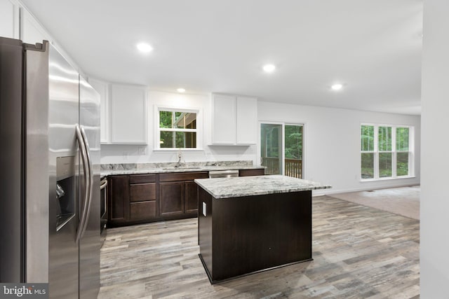 kitchen featuring white cabinets, stainless steel fridge, a center island, and light hardwood / wood-style floors