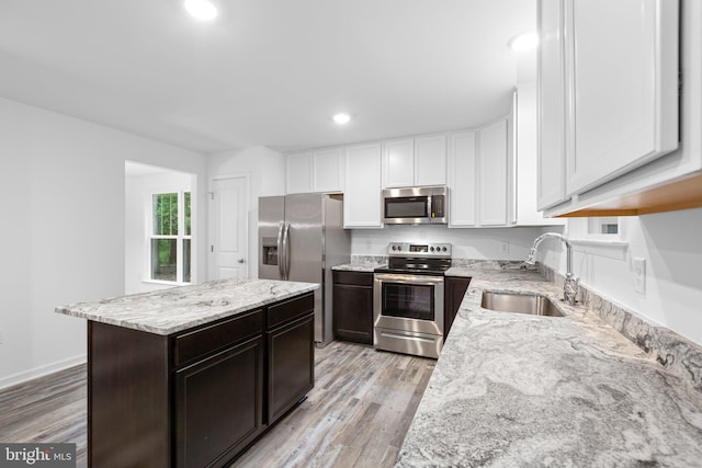 kitchen with dark brown cabinetry, sink, a center island, stainless steel appliances, and light hardwood / wood-style flooring