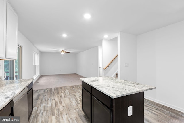 kitchen featuring light stone countertops, light hardwood / wood-style flooring, a kitchen island, and stainless steel dishwasher