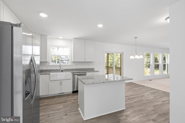 kitchen with appliances with stainless steel finishes, dark wood-type flooring, white cabinets, a center island, and plenty of natural light