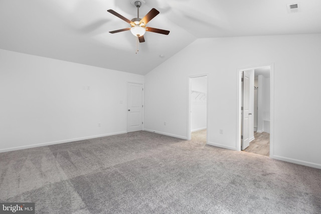 unfurnished bedroom with light carpet, vaulted ceiling, ceiling fan, a spacious closet, and a closet