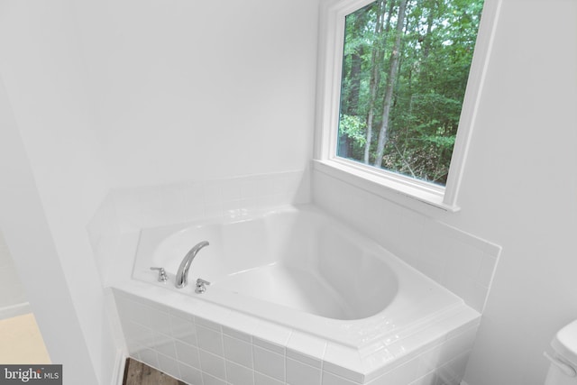 bathroom with a relaxing tiled tub and toilet