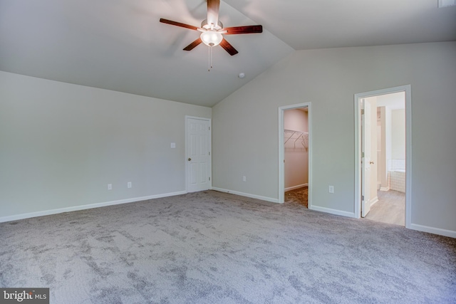 unfurnished bedroom featuring a walk in closet, light colored carpet, ceiling fan, and lofted ceiling