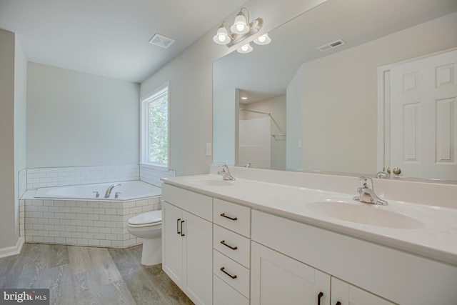 full bathroom with shower with separate bathtub, vanity, hardwood / wood-style flooring, and toilet