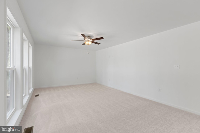 carpeted spare room featuring ceiling fan and a healthy amount of sunlight