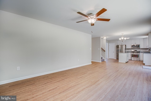 unfurnished living room featuring light hardwood / wood-style floors and ceiling fan with notable chandelier