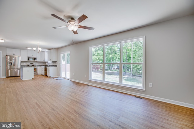 unfurnished living room featuring ceiling fan with notable chandelier, light hardwood / wood-style flooring, and sink