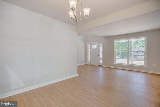 unfurnished room with an inviting chandelier and light wood-type flooring