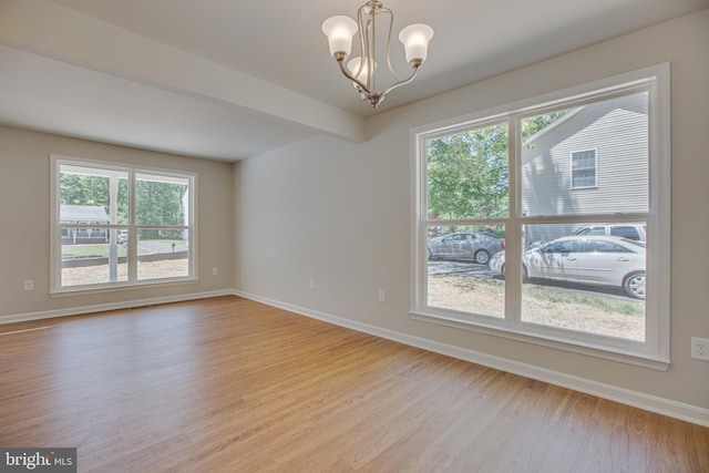 unfurnished room featuring light wood-type flooring, a wealth of natural light, and a chandelier