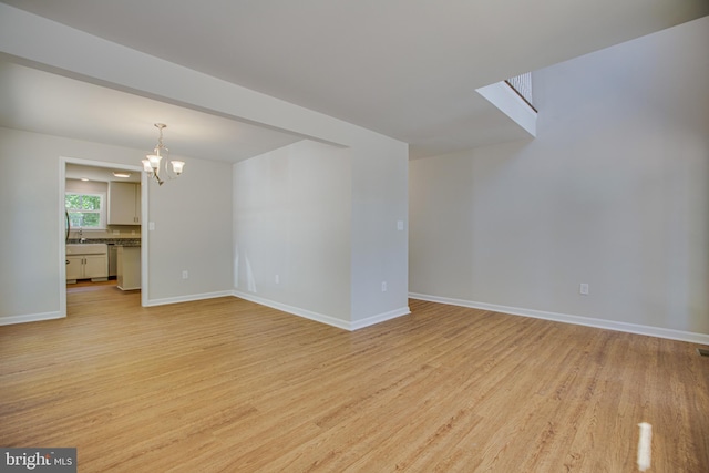 unfurnished room featuring sink, a chandelier, and light wood-type flooring