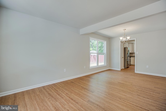 spare room with beamed ceiling, a chandelier, and light hardwood / wood-style flooring