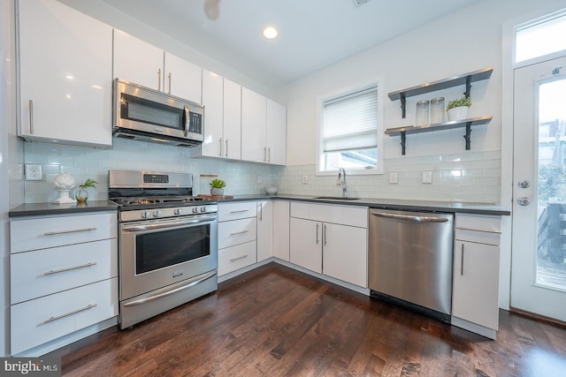 kitchen with sink, dark hardwood / wood-style floors, tasteful backsplash, white cabinetry, and stainless steel appliances