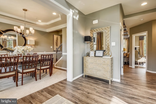 dining room featuring a raised ceiling, ornamental molding, a chandelier, and hardwood / wood-style flooring