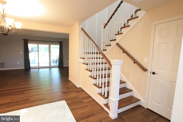 stairs featuring hardwood / wood-style floors and an inviting chandelier