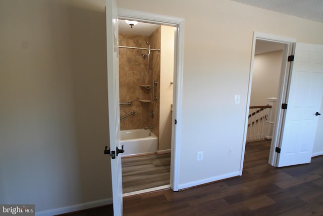 bathroom featuring a textured ceiling, tiled shower / bath combo, and hardwood / wood-style flooring