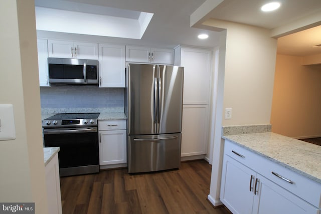 kitchen featuring decorative backsplash, appliances with stainless steel finishes, dark hardwood / wood-style flooring, light stone counters, and white cabinetry