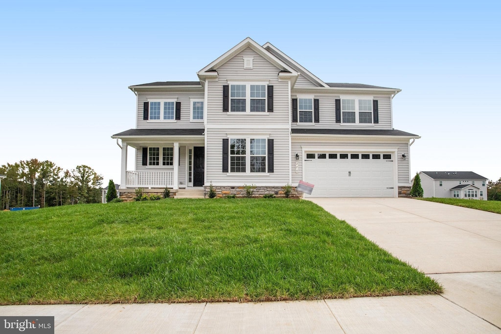 view of front of property with covered porch, a garage, and a front lawn