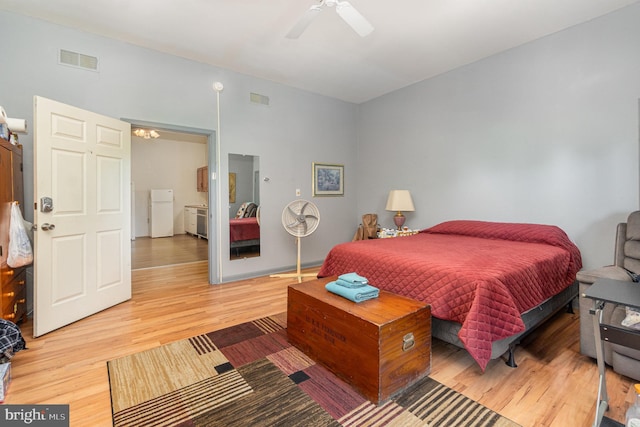 bedroom with hardwood / wood-style floors, white refrigerator, and ceiling fan