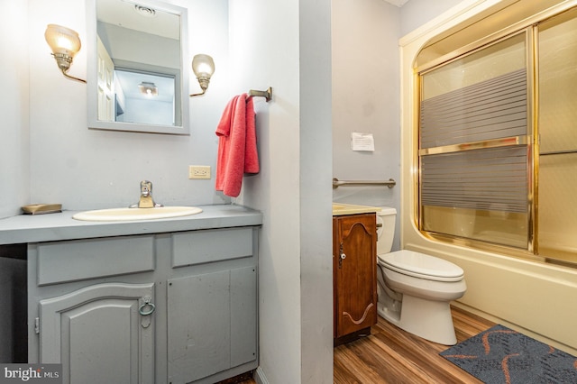 full bathroom featuring vanity, toilet, wood-type flooring, and bath / shower combo with glass door