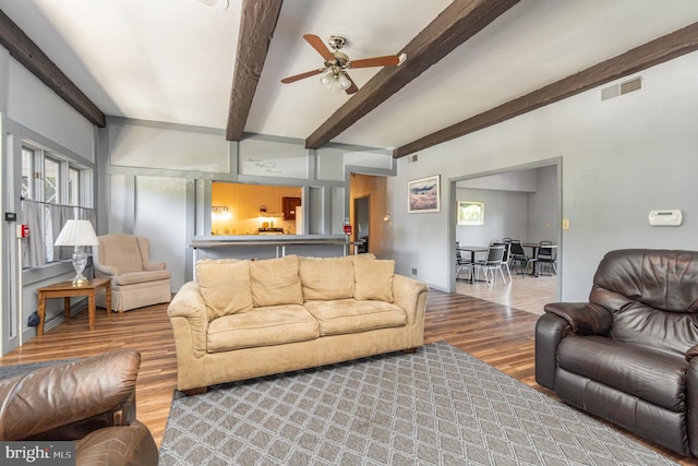 living room featuring beamed ceiling, hardwood / wood-style flooring, and ceiling fan