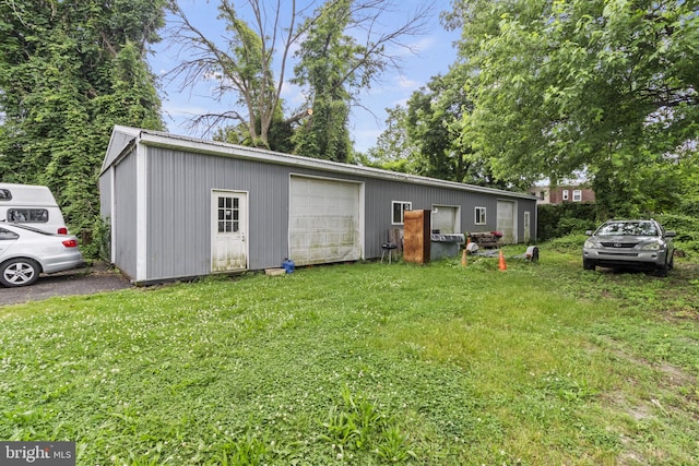 exterior space featuring a garage, a front lawn, and an outdoor structure