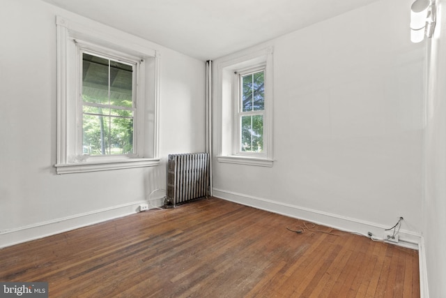 spare room featuring dark hardwood / wood-style floors and radiator