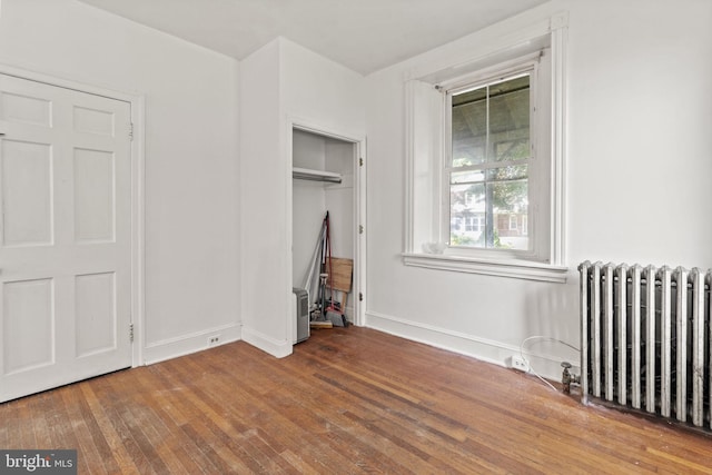 unfurnished bedroom featuring radiator, a closet, and wood-type flooring