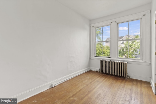 unfurnished room featuring light hardwood / wood-style floors and radiator heating unit