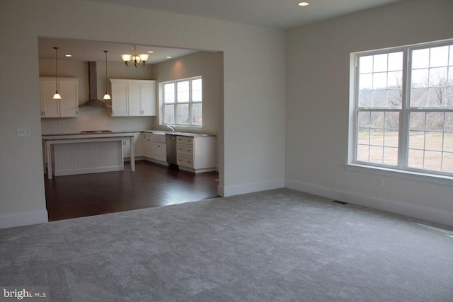 kitchen featuring white cabinets, decorative light fixtures, plenty of natural light, and wall chimney range hood