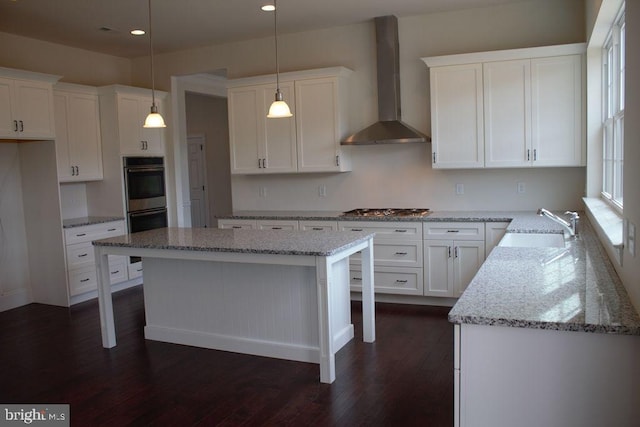 kitchen with white cabinetry, wall chimney exhaust hood, hanging light fixtures, dark hardwood / wood-style floors, and appliances with stainless steel finishes