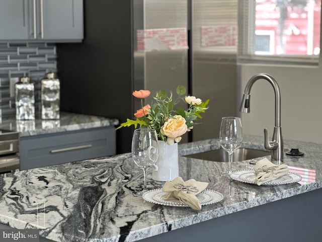 interior details featuring gray cabinets, light stone countertops, and sink