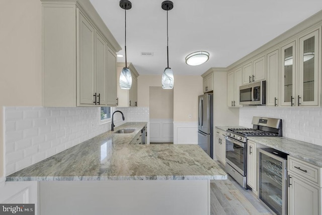 kitchen featuring sink, beverage cooler, stainless steel appliances, kitchen peninsula, and pendant lighting