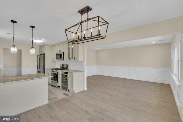 kitchen featuring appliances with stainless steel finishes, light wood-type flooring, beverage cooler, and pendant lighting