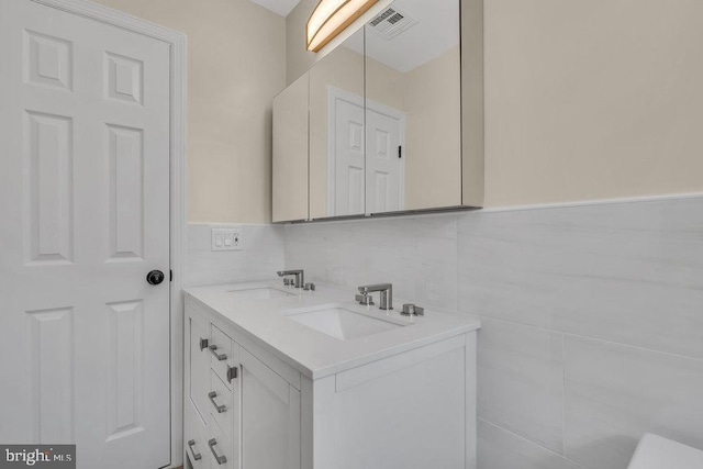 bathroom with vanity and tile walls