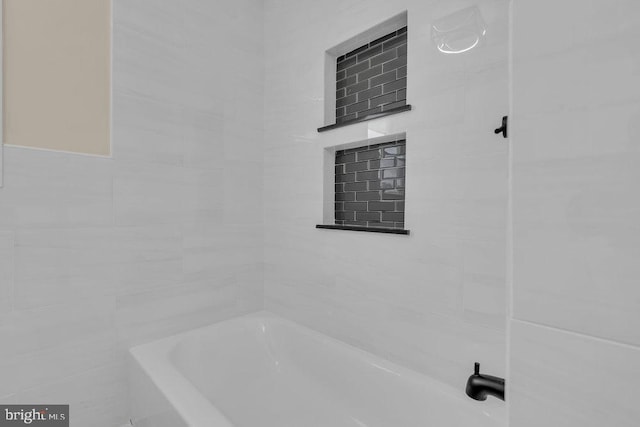 bathroom featuring tiled shower / bath and tile walls