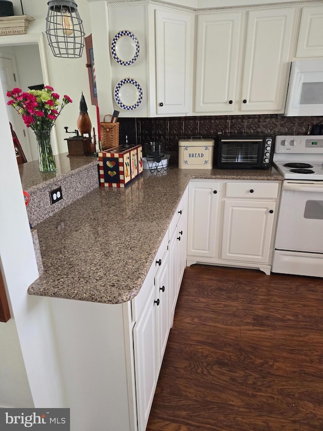 kitchen with decorative backsplash, white appliances, dark stone countertops, white cabinets, and dark hardwood / wood-style floors