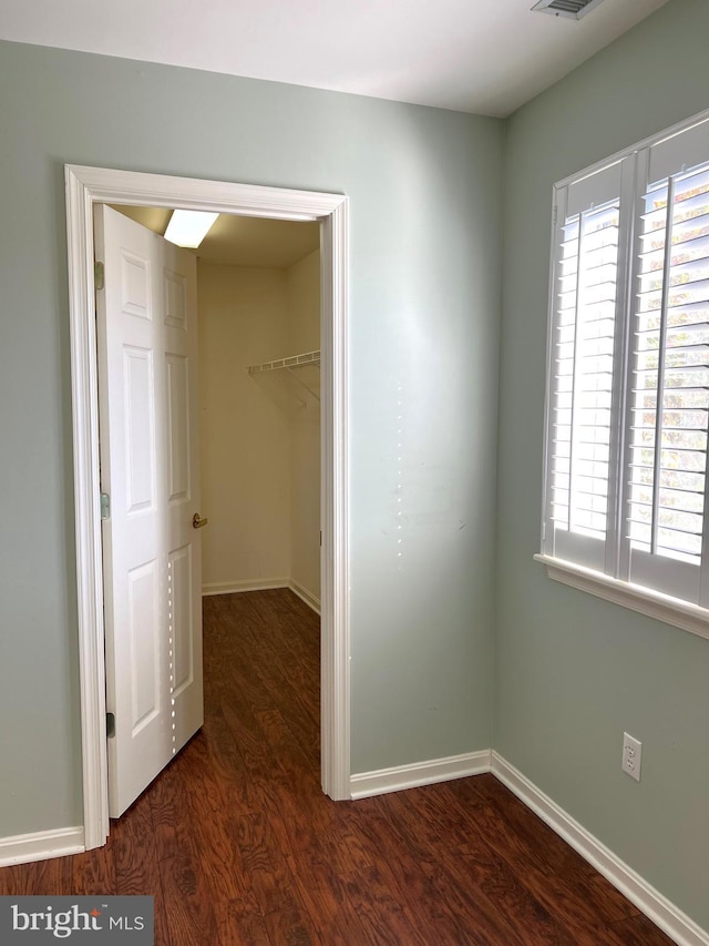 unfurnished bedroom featuring dark hardwood / wood-style floors, a walk in closet, and a closet