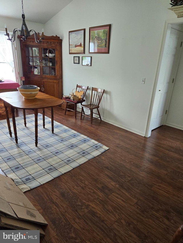 dining space featuring vaulted ceiling, hardwood / wood-style flooring, and an inviting chandelier