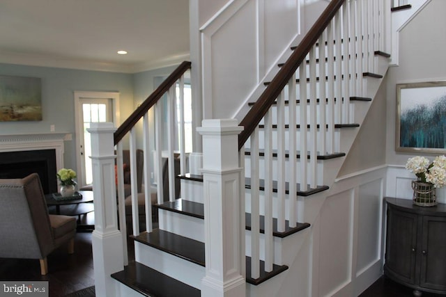 stairway with crown molding and wood-type flooring