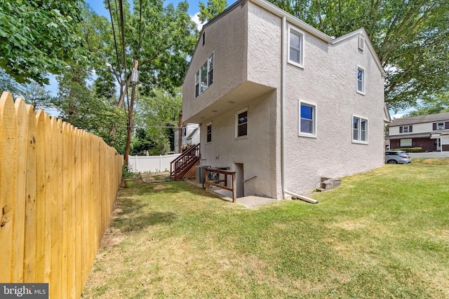 back of property featuring central AC unit and a yard