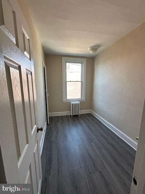 unfurnished room with radiator heating unit and dark hardwood / wood-style flooring