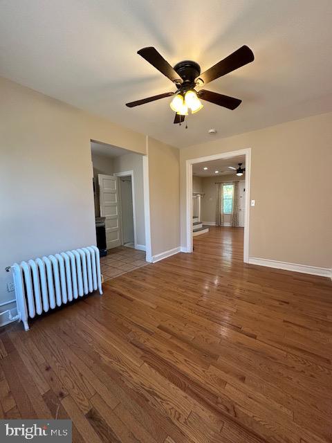 unfurnished room with radiator, ceiling fan, and dark hardwood / wood-style floors