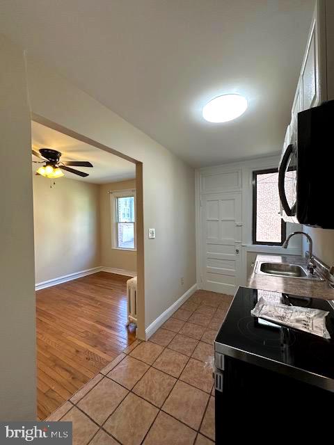 kitchen featuring radiator heating unit, ceiling fan, light wood-type flooring, electric stove, and sink