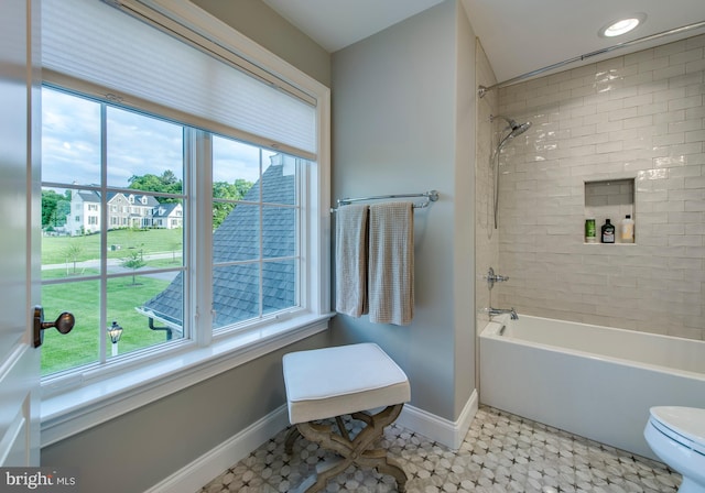 bathroom featuring tile patterned floors, plenty of natural light, toilet, and tiled shower / bath combo