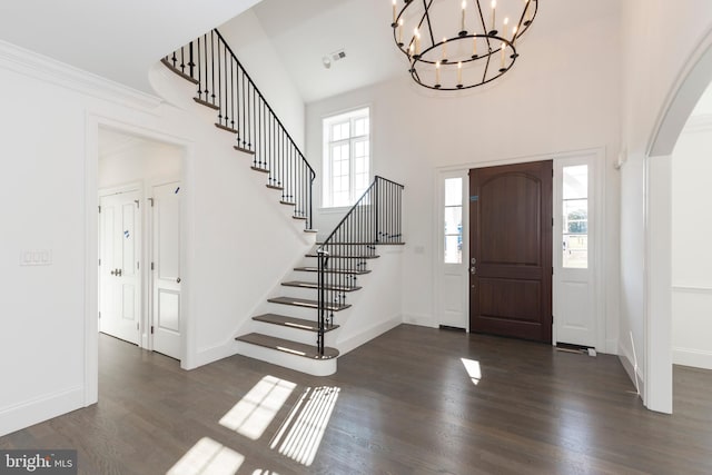 entrance foyer featuring plenty of natural light, dark hardwood / wood-style floors, a towering ceiling, and an inviting chandelier