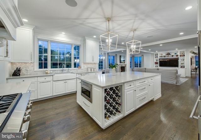 kitchen with appliances with stainless steel finishes, dark hardwood / wood-style flooring, sink, white cabinets, and hanging light fixtures